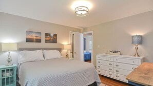 Een slaapkamer met een bed, nachtkastjes, een kaptafel en een spiegel.
