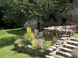 A stone wall with a flag, a tree, and a garden with various plants. - La Rosière 2. A heavenly place in the midst of nature, peace and quiet. (Auzelles)