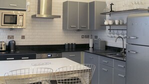 Una cucina moderna con elettrodomestici in acciaio inossidabile, un piano di lavoro bianco e un'area pranzo con sedie in metallo.