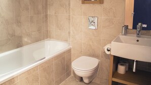 Un bagno con vasca, WC, lavandino e specchio.