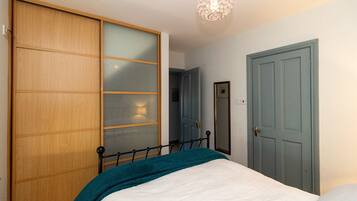 A bedroom with a bed, a wardrobe, a door, and a hanging light fixture.