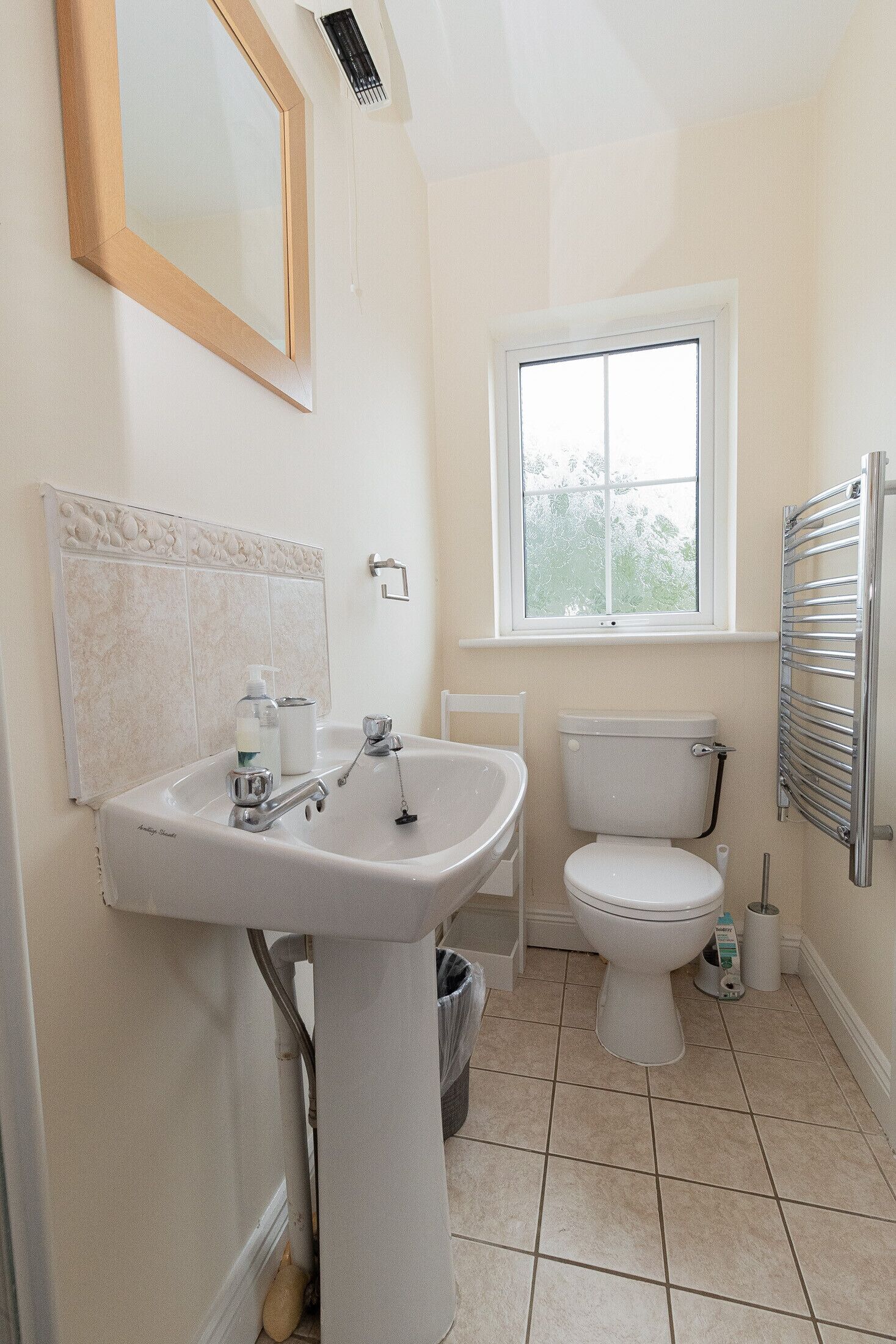 A bathroom with a sink, toilet, and window.