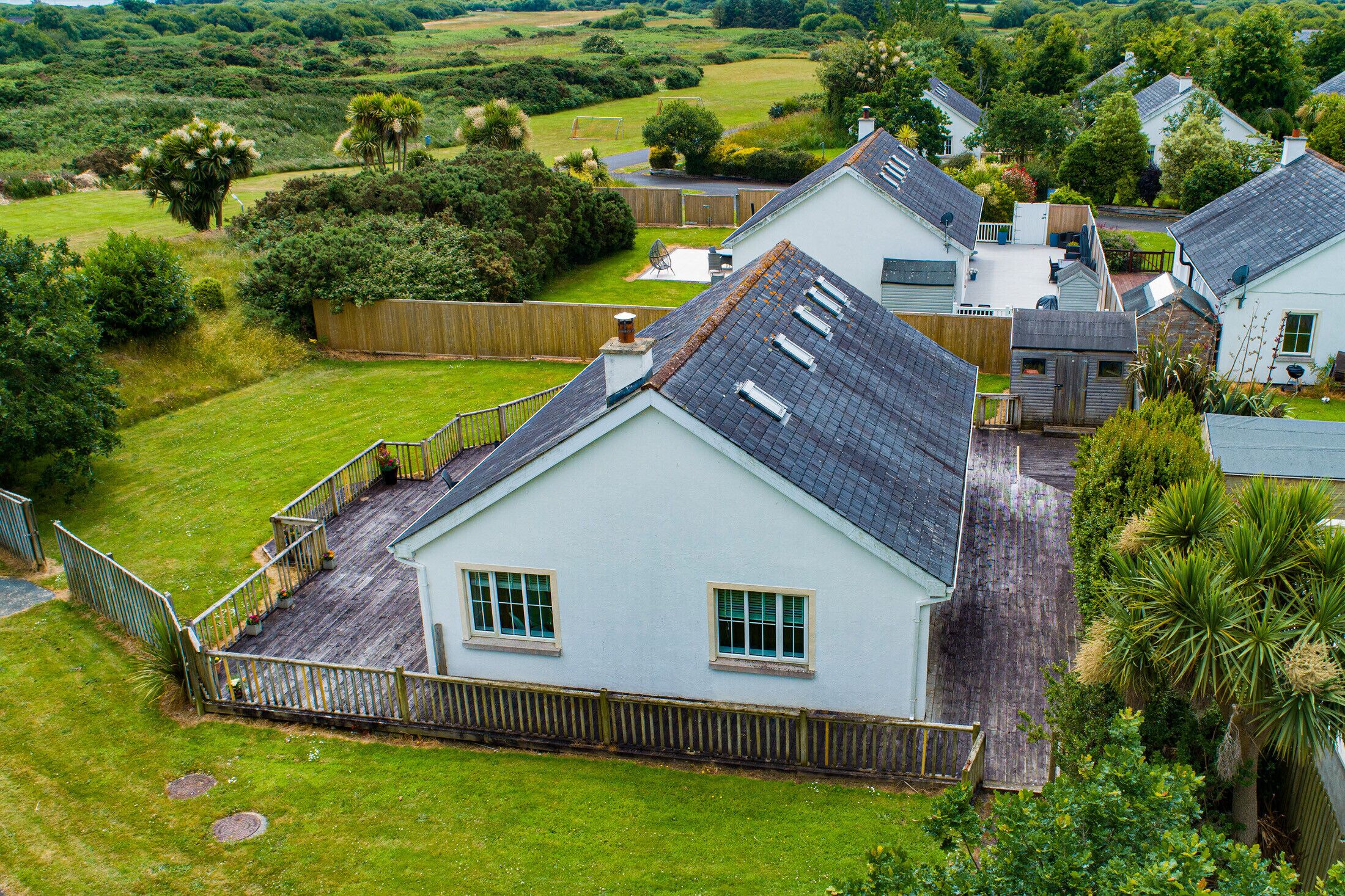 A residential area with houses, a wooden deck, and a grassy yard.