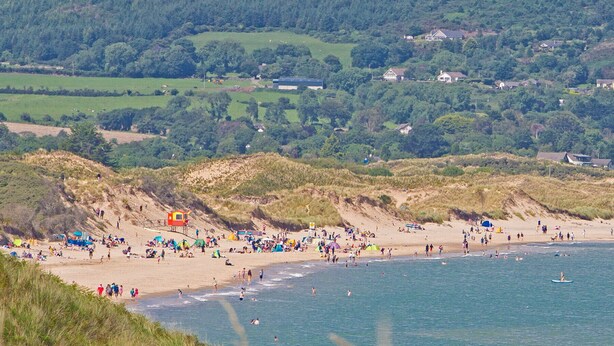 Une plage avec des gens, des tentes et un poste de surveillance pour les sauveteurs.