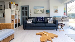 Un salon moderne avec un canapé bleu foncé, des meubles en osier et une table basse en bois.
