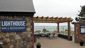 Un edificio de piedra con un letrero que dice "Lighthouse Bar & Restaurant" y un patio exterior con mesas y sillas.