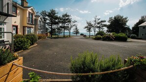 Una calle residencial con casas, cielo despejado y vista distante al mar.