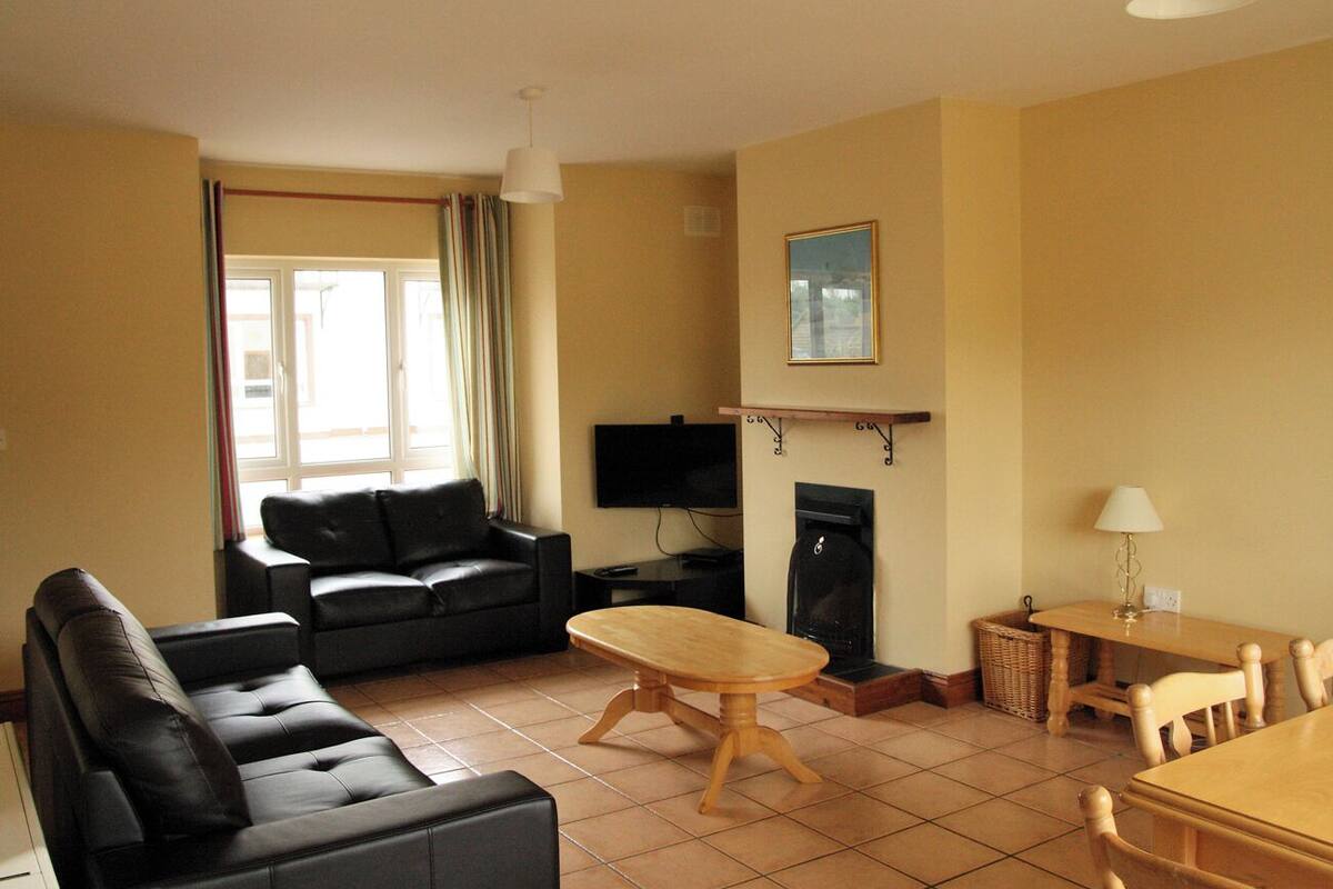 A living room with a sofa, a wooden table, a TV, and a fireplace.