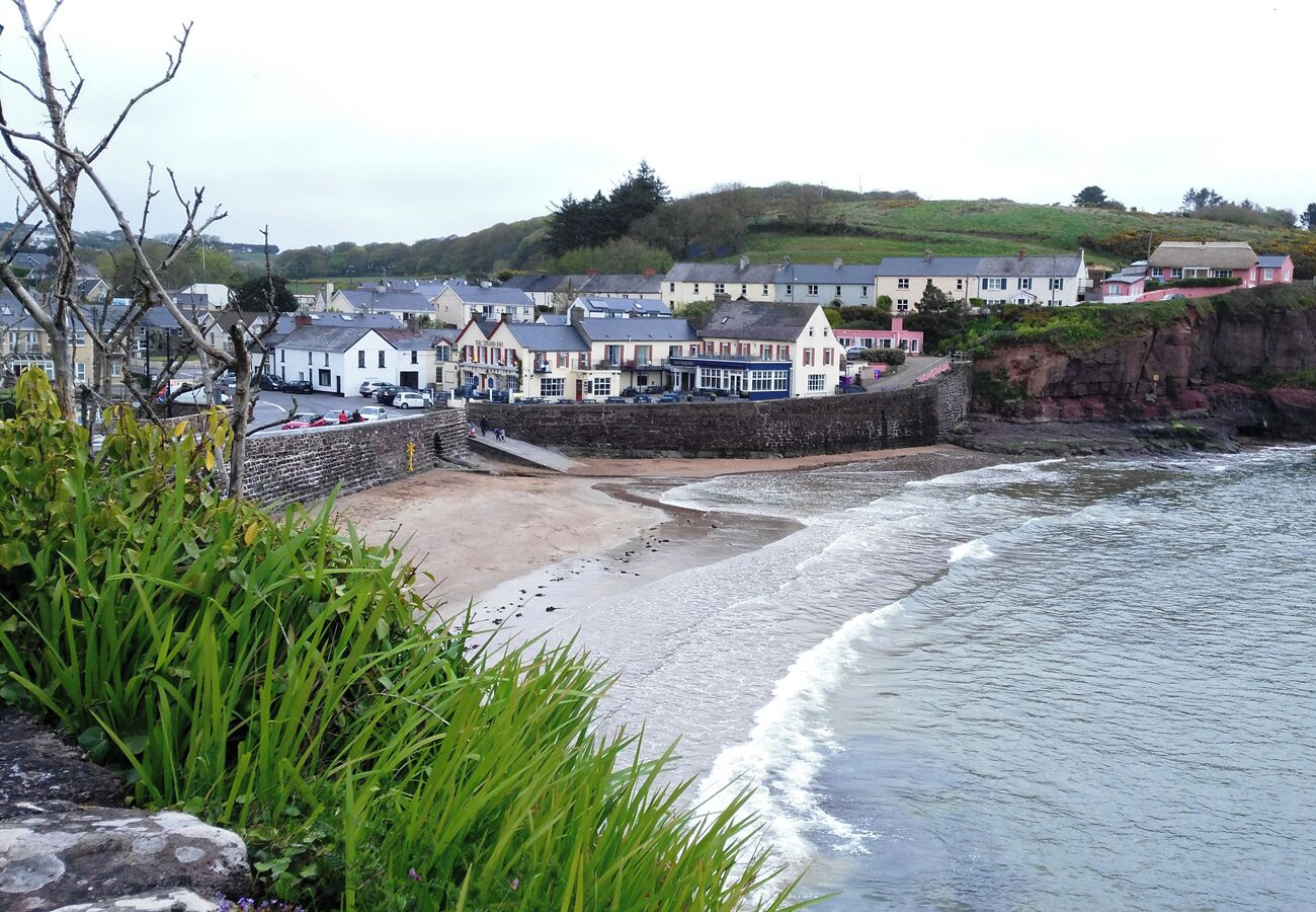 A coastal town with buildings along the shore, a sandy beach, and waves crashing onto the beach.