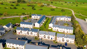 Zona residencial con varias casas, un área de estacionamiento y vista al mar.