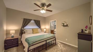 Un dormitorio con cama, mesita de noche, ventilador de techo y cómoda.