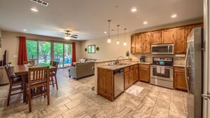 A modern kitchen with wooden cabinets, stainless steel appliances, and a dining area with a table and chairs. - Riverfront Fun Rg 111 2 Bedroom Condo by RedAwning (New Braunfels)