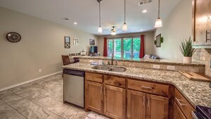 A kitchen with granite countertops, wooden cabinets, a dishwasher, and pendant lighting. - Riverfront Fun Rg 111 2 Bedroom Condo by RedAwning (New Braunfels)