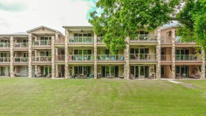A multi-story hotel with outdoor seating areas and a well-maintained lawn. - Riverfront Fun Rg 111 2 Bedroom Condo by RedAwning (New Braunfels)