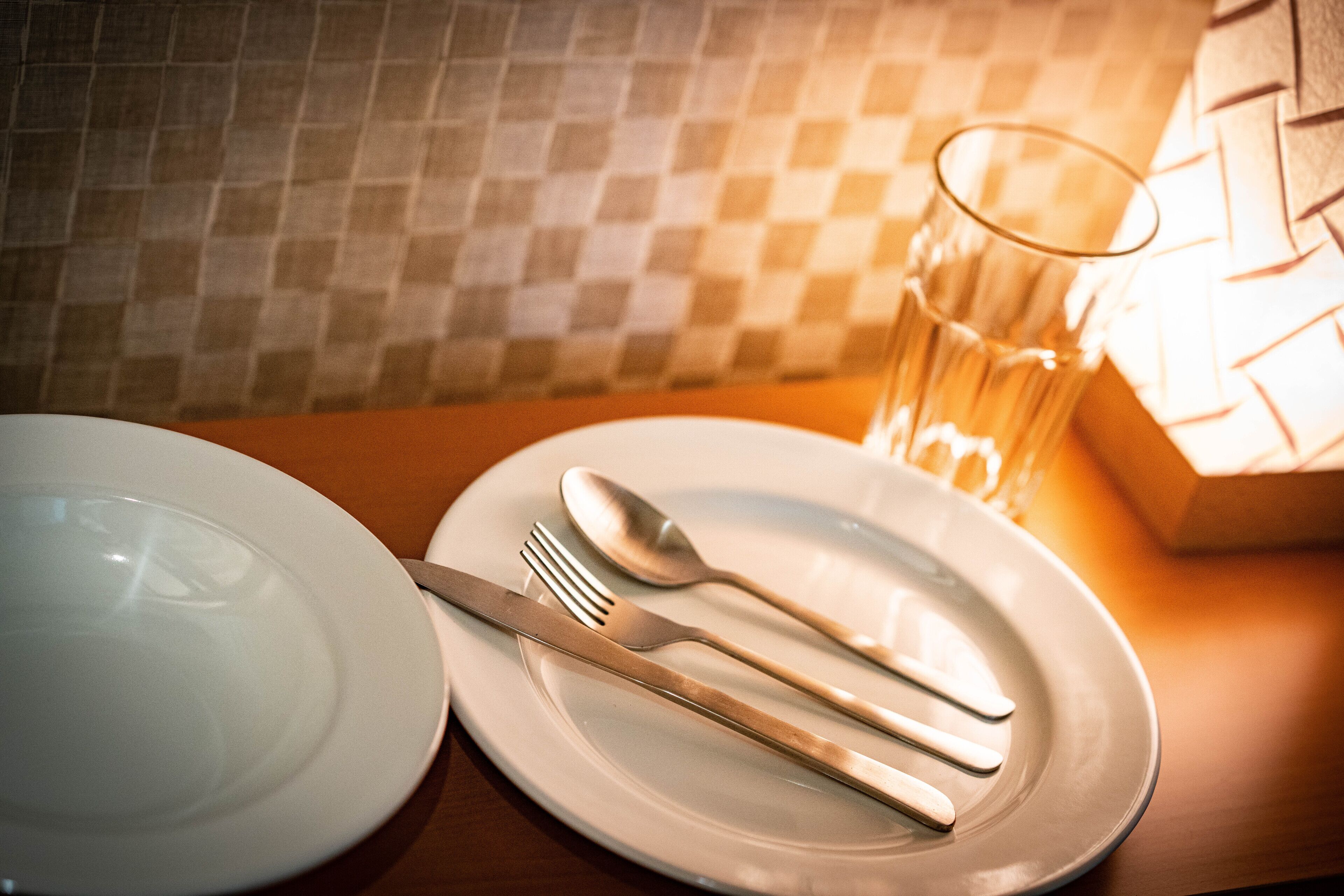 A dining table with a plate, a fork, a knife, and a glass.