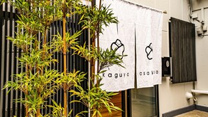 A building with bamboo plants in front, a sign with Japanese characters, and a tiled floor.