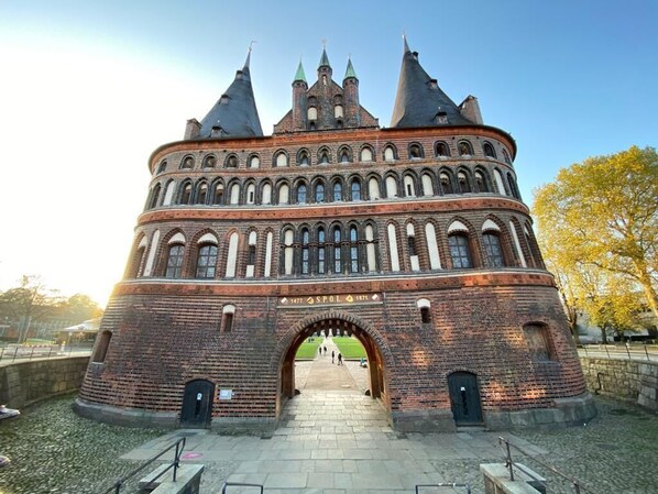 A historic brick building with a central archway, multiple towers, and a clear sky.