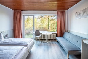 Une chambre d’hôtel moderne avec une grande fenêtre, une table ronde et un canapé.