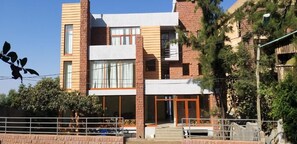 Un edifici modern de dos pisos amb façana de maó, finestres grans i una entrada visible amb escales.