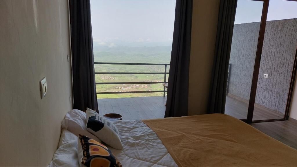 Un dormitorio con cama, mesita de noche y vistas a un balcón con barandilla.