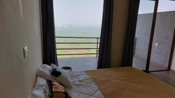 Un dormitorio con cama, mesita de noche y vistas a un balcón con barandilla.