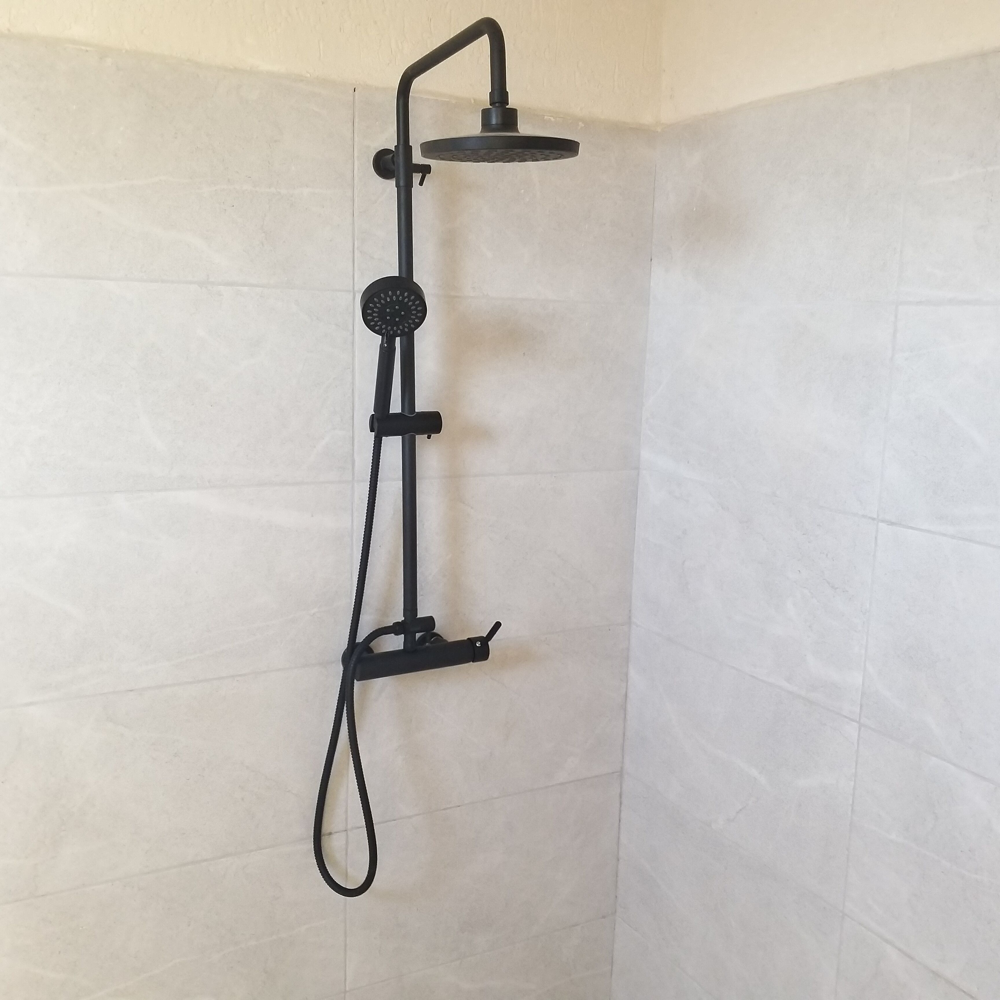 Una ducha con cabezal de ducha manual y un accesorio tipo lluvia.