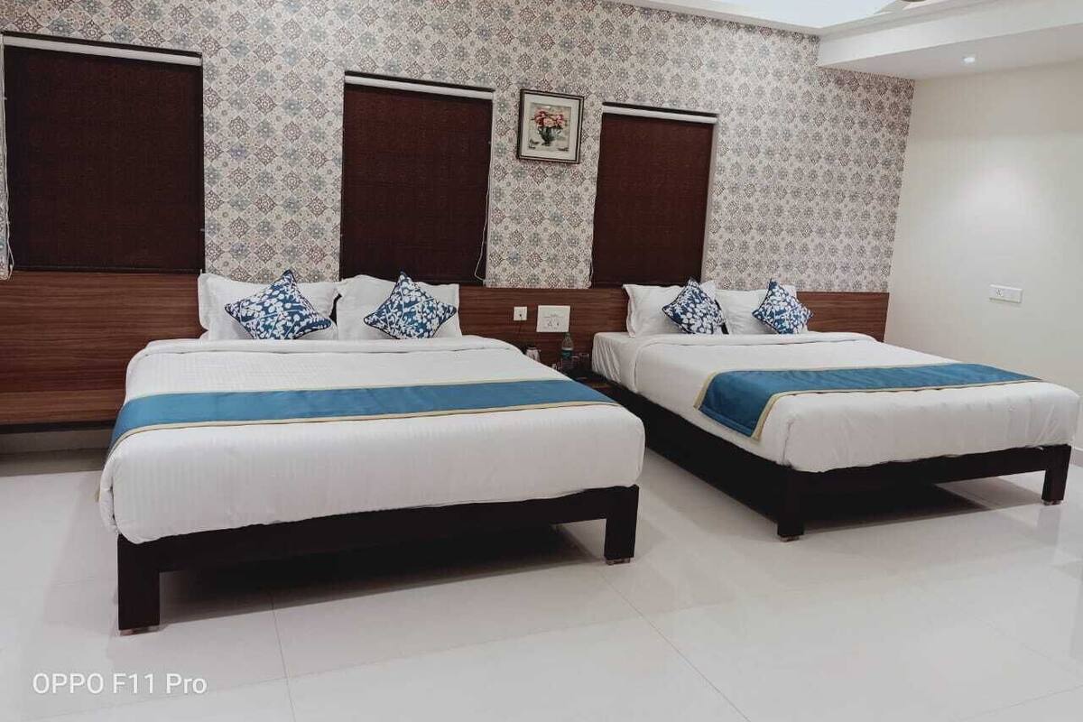 Quarto de hotel com duas camas, ventoinha no teto e papel de parede estampado.