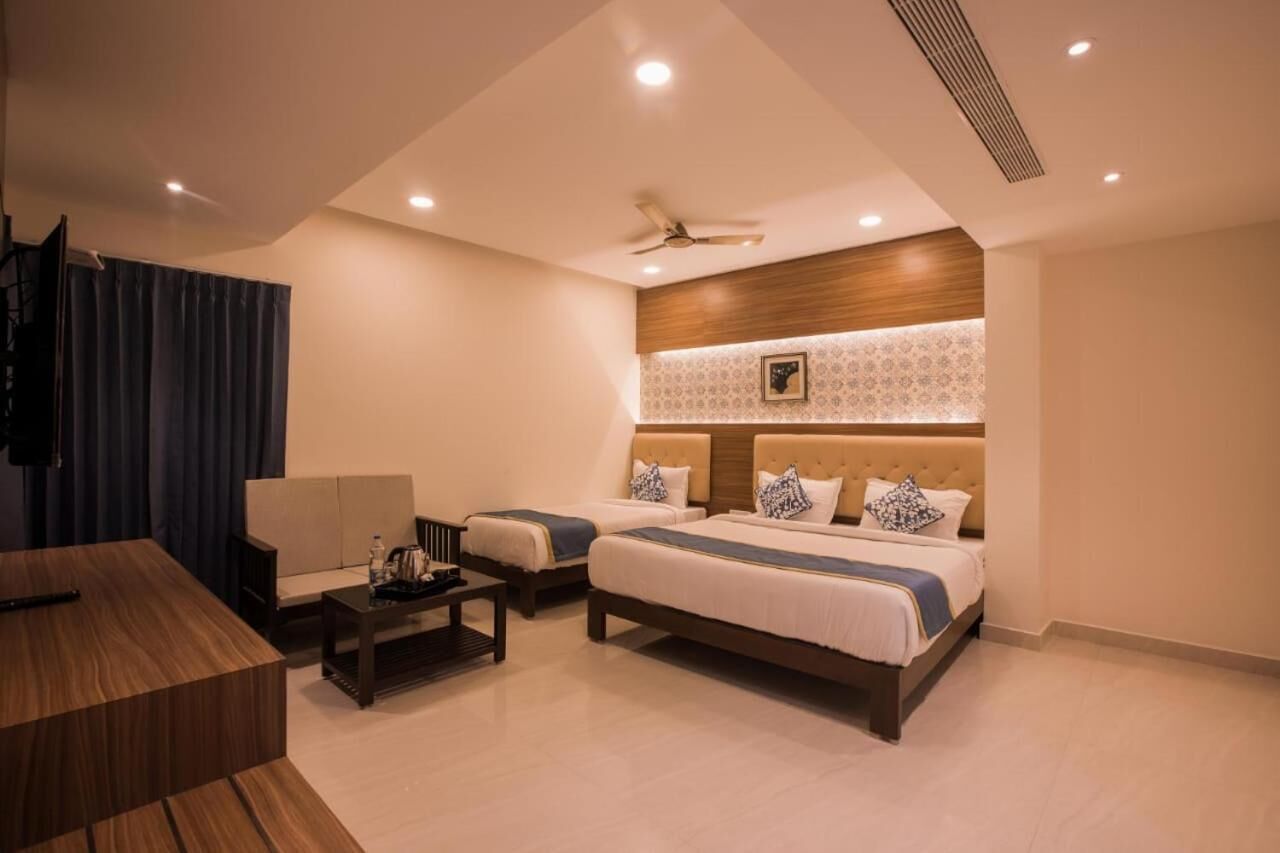 A hotel room with two beds, a desk, and a ceiling fan.