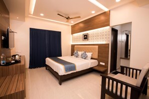 A modern hotel room with a large bed, a TV, a desk, and a chair. - Hotel SMA Grand Inn (Chennai)
