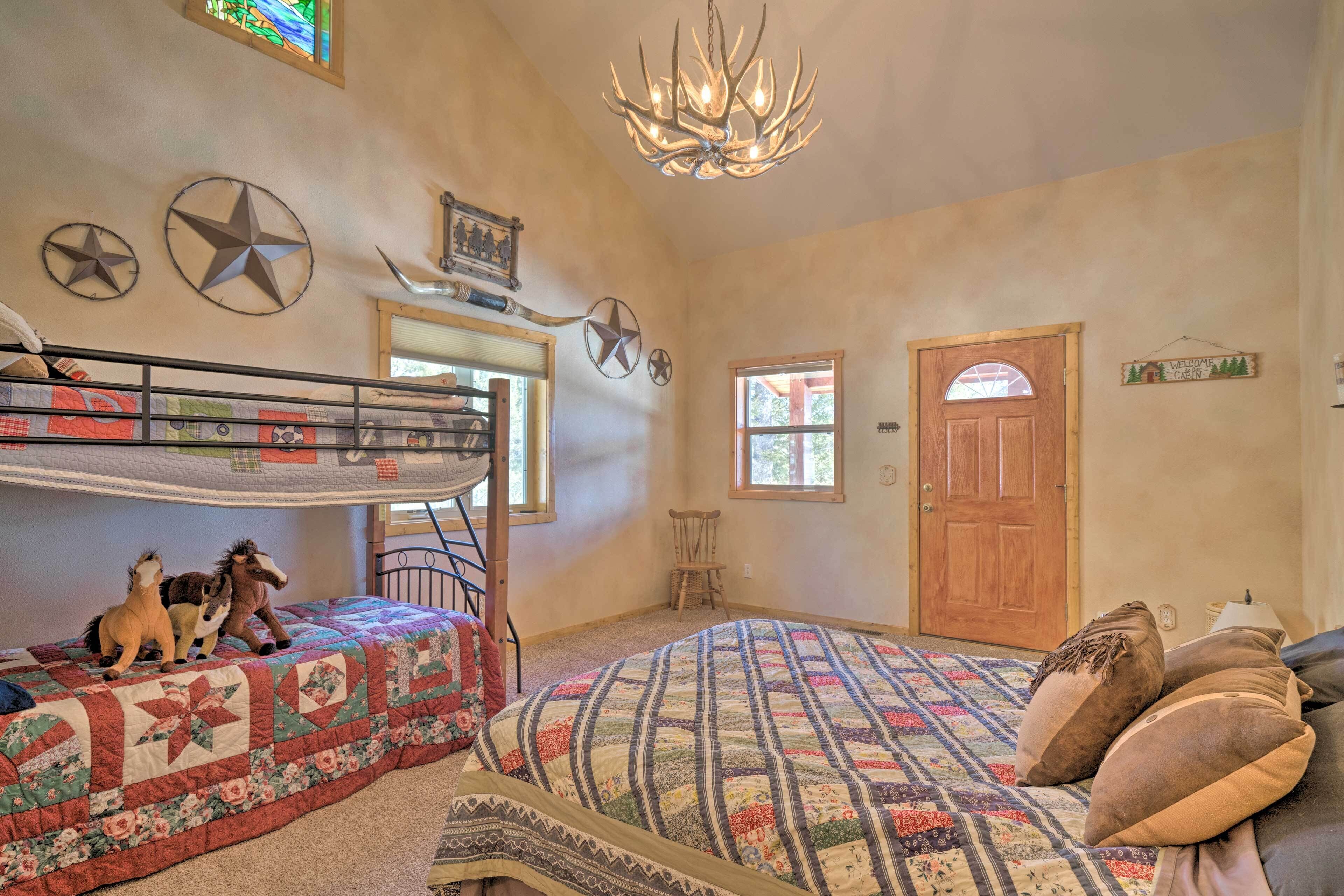 Quarto com beliches, cama acolchoada, lustre e porta de madeira.