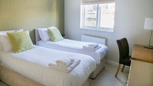 Een hotelkamer met twee bedden, een bureau, een stoel en een raam met uitzicht.