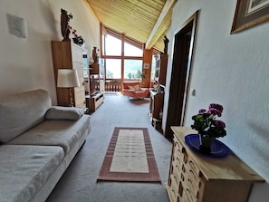 A cozy living room with a sofa, a wooden cabinet with drawers, a television, and a decorative plant.