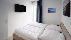 A bedroom with a bed, a television mounted on the wall, and a window with curtains. - Baabe villas ensemble VE 19 sea view romanticism Ref. 215919 (Baabe)