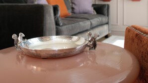 Un salon comprenant un canapé, une table basse agrémentée d’un objet décoratif, un miroir fixé au mur et des œuvres d’art encadrées.