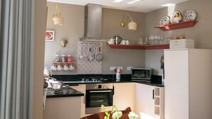 Une cuisine moderne équipée d’une cuisinière, d’un four et d’un micro-ondes, un coin repas avec une table et des chaises, et un salon avec un canapé et un vase de fleurs.