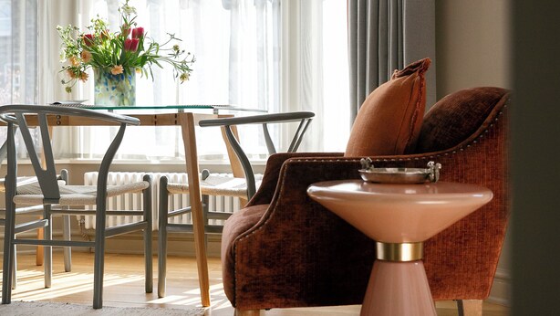 Un coin repas avec une table, des chaises et un vase de fleurs.