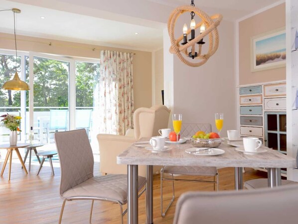 A modern dining area with a marble table, cushioned chairs, and a fruit bowl.