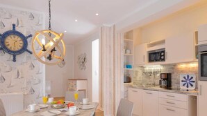 Una cucina moderna con mobili bianchi, forno a microonde integrato e macchina per il caffè.