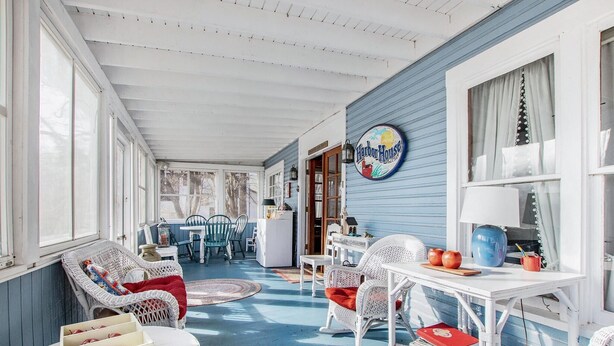 A cozy porch with wicker furniture, a table with apples and books, and a sign reading "Harbor House". - WELCOME TO HARBOR HOUSE!  STEP BACK IN TIME AND RELAX AT THE BEACH... (Holland)