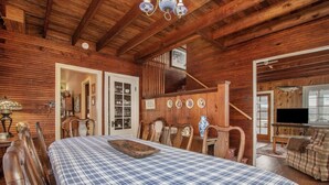 A wooden cabin interior with a large bed, dining table, and chairs. There is a staircase leading to an upper level, and a television in the living area. - WELCOME TO HARBOR HOUSE!  STEP BACK IN TIME AND RELAX AT THE BEACH... (Holland)