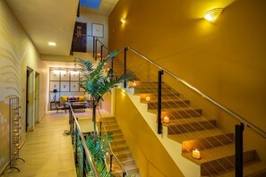 A staircase with a railing, a wall-mounted light fixture, and a plant.