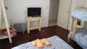 Una camera da letto con un letto, una TV su un tavolino e una porta che dà su un'altra stanza.
