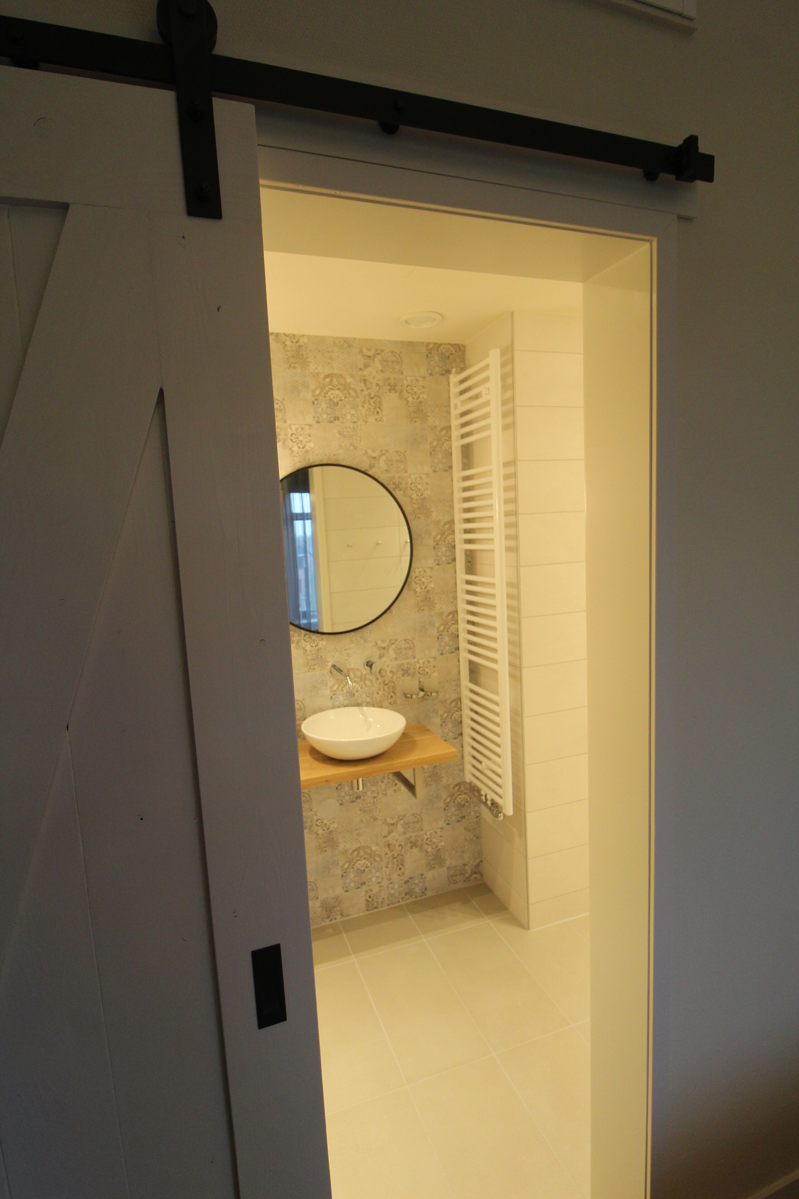 Een badkamer met een witte wastafel, een ronde spiegel en een handdoekhouder.