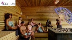 A wooden sauna with people sitting on benches and a person holding a fan. - Polderhuis Bed & Breakfast (Bergschenhoek)