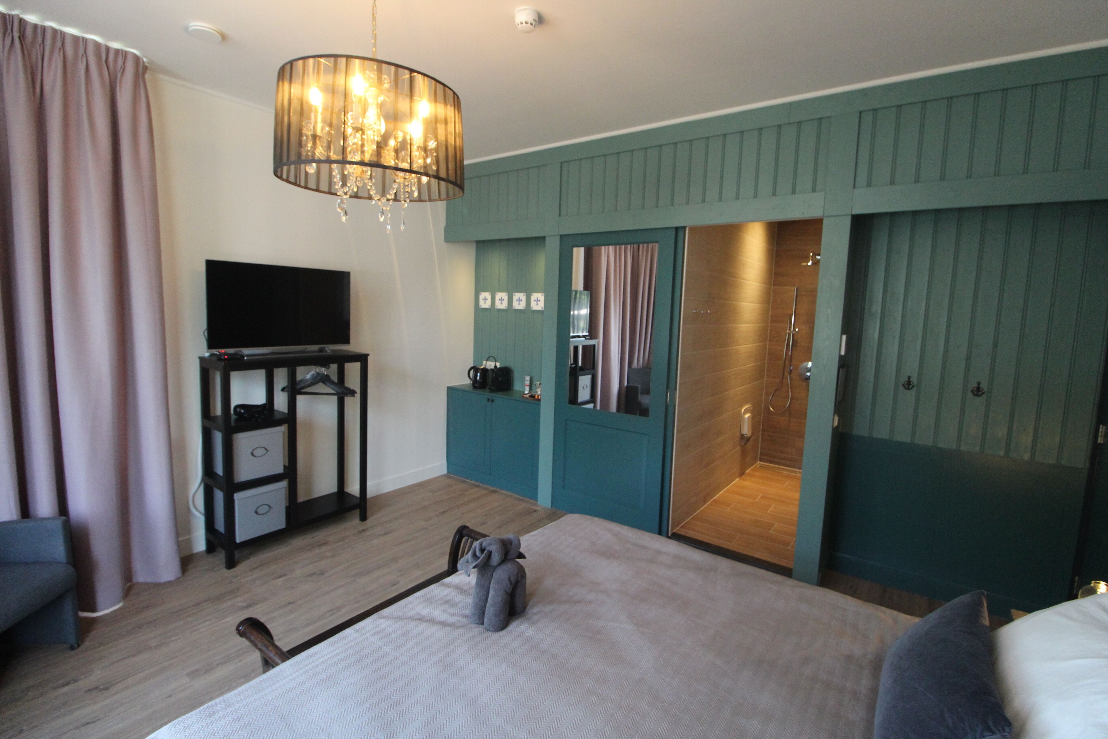 Une chambre d’hôtel comprenant un lit, un bureau avec une télévision, une armoire et un espace douche.
