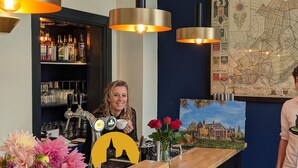 A bar area with a map on the wall, a bar counter with a coffee machine, and a display of flowers. - Polderhuis Bed & Breakfast (Bergschenhoek)