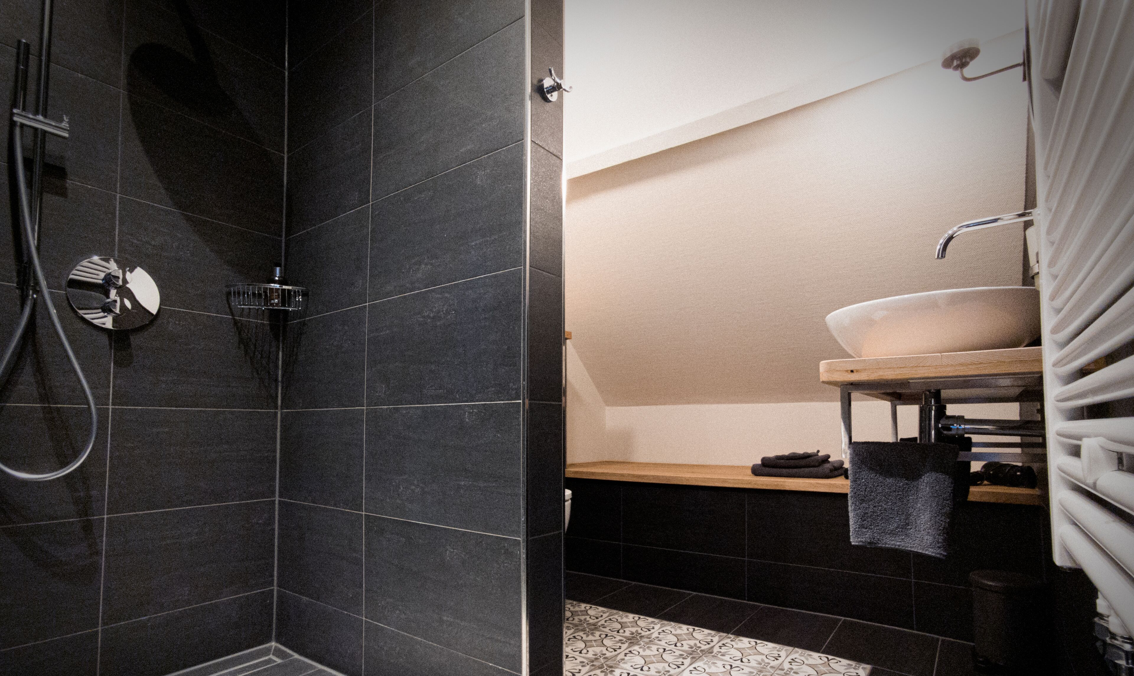 Een moderne badkamer met een douche, wastafel en handdoekrek.
