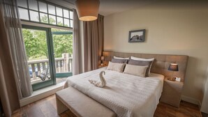 A hotel room with a large bed, a bench, a balcony with a view, and a framed picture on the wall. - Polderhuis Bed & Breakfast (Bergschenhoek)
