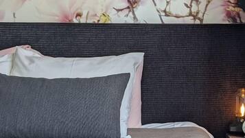 A bedroom with a large floral wall mural, a dark headboard, and a bedside lamp.