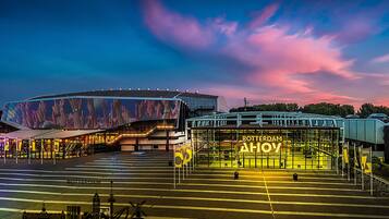 A modern stadium with a distinctive roof structure and a sign reading "Rotterdam Ahoy".